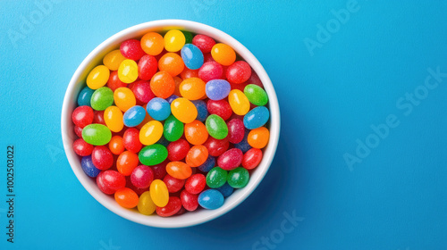 Assorted multicolored jelly beans in a white bowl with a blue backdrop