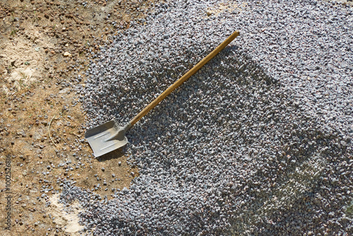 A shovel rests on a pile of gravel, working with gravel at a construction site, loading gravel, close-up.