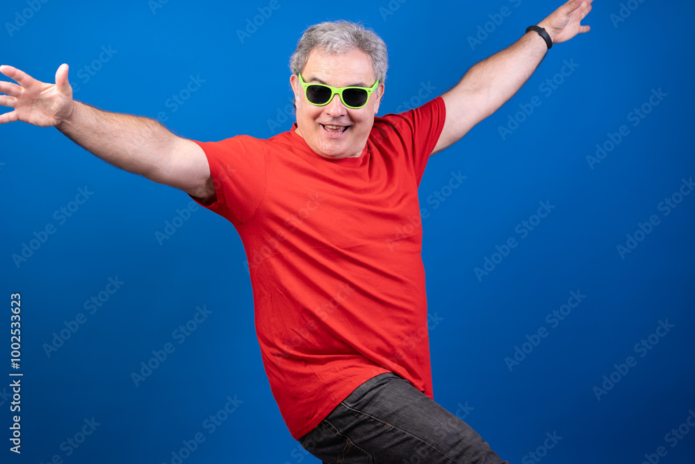 Naklejka premium A man in a red shirt and green sunglasses is smiling and posing for a picture