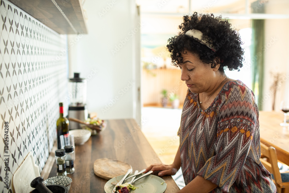 Middle-aged woman in kitchen looking pensive while cleaning up after meal Middle-aged woman in kitchen looking pensive while cleaning up after meal