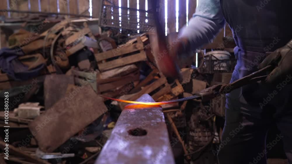 An old man shapes knife from heated iron in his work shop An old man shapes knife from heated iron in his work shop