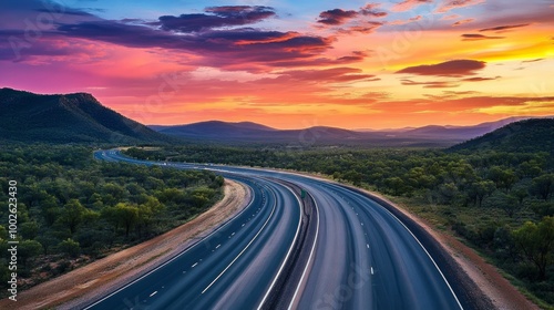 A multi-lane highway situated in the Australian outback, framed by colorful clouds and a vivid evening sky