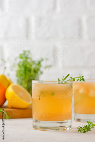 Homemade pear drink lemonade with lemon, rosemary, thyme and ice in a glasses on a light table. Healthy drink, sugar and alcohol free. Vertical orientation.