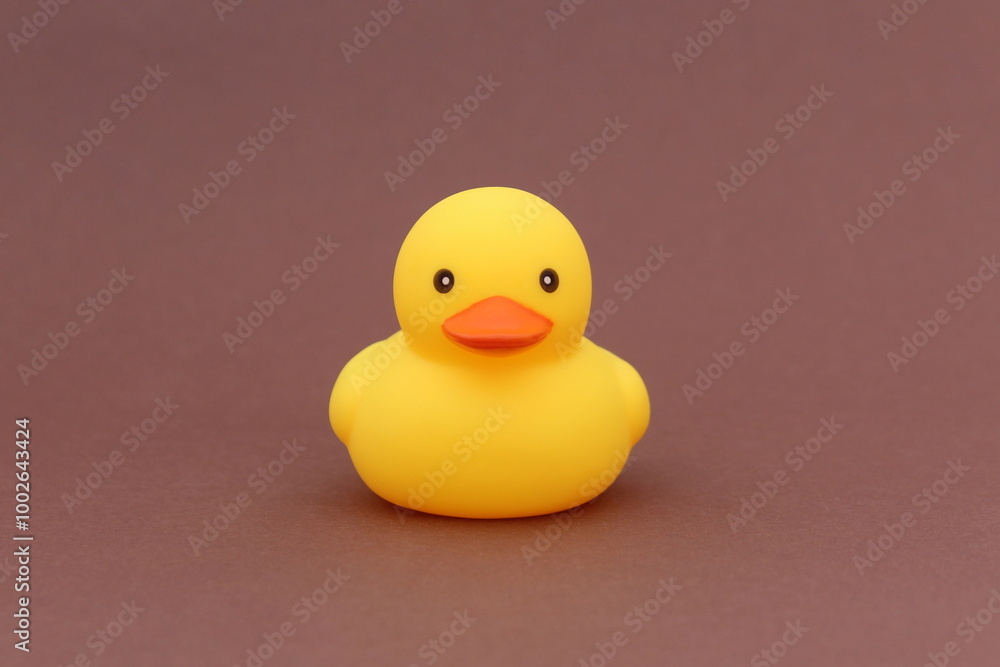 A yellow rubber duck stands on a brown background. A yellow rubber duck stands on a brown background.