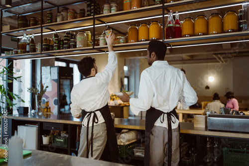 Rear view of male chefs working together in commercial kitchen at restaurant photo