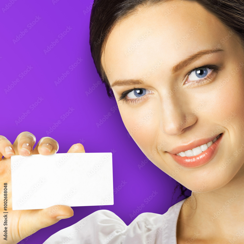 Portrait of smiling beautiful brunette woman showing advertising white blank mockup mock up empty businesscard plastic credit card, with ad text area, isolated violet purple background. Square image. Portrait of smiling beautiful brunette woman showing advertising white blank mockup mock up empty businesscard plastic credit card, with ad text area, isolated violet purple background. Square image.