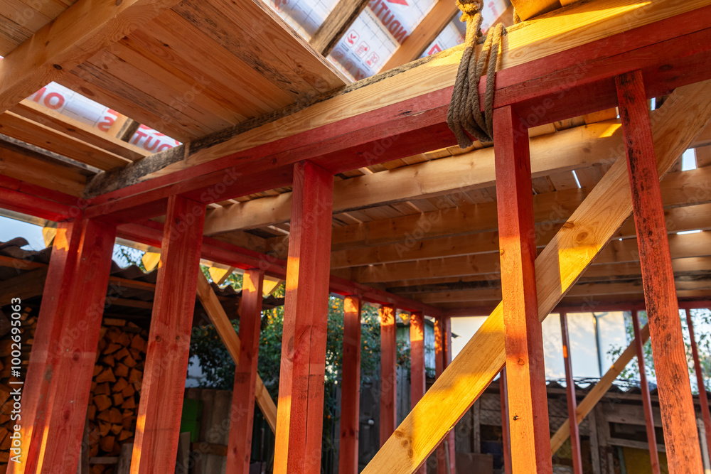 Under-construction residential wooden frame home located near a forest. Commencement of a new construction project for a cozy house or a mountain cottage. Idea of contemporary ecological construction. Under-construction residential wooden frame home located near a forest. Commencement of a new construction project for a cozy house or a mountain cottage. Idea of contemporary ecological construction.