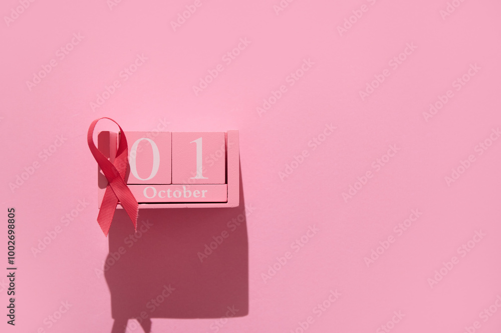 Pink ribbon on October calendar block against pink background symbolizing breast cancer awareness month Pink ribbon on October calendar block against pink background symbolizing breast cancer awareness month