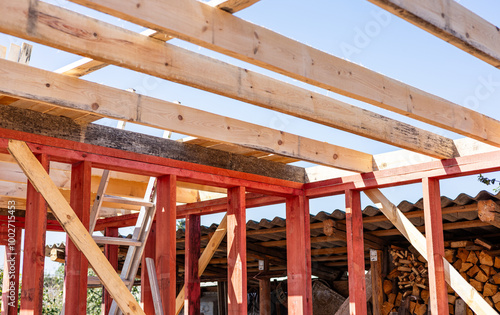 Under-construction residential wooden frame home located near a forest. Commencement of a new construction project for a cozy house or a mountain cottage. Idea of contemporary ecological construction.