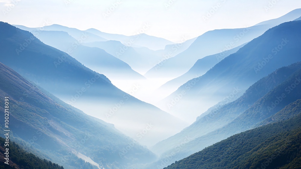 Obraz premium Misty mountain range with a valley in the distance, bathed in a soft blue light.