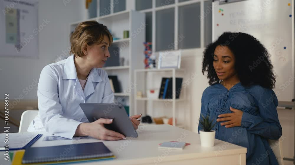 Gynecologist showing baby ultrasound image on tablet to happy pregnant patient Gynecologist showing baby ultrasound image on tablet to happy pregnant patient