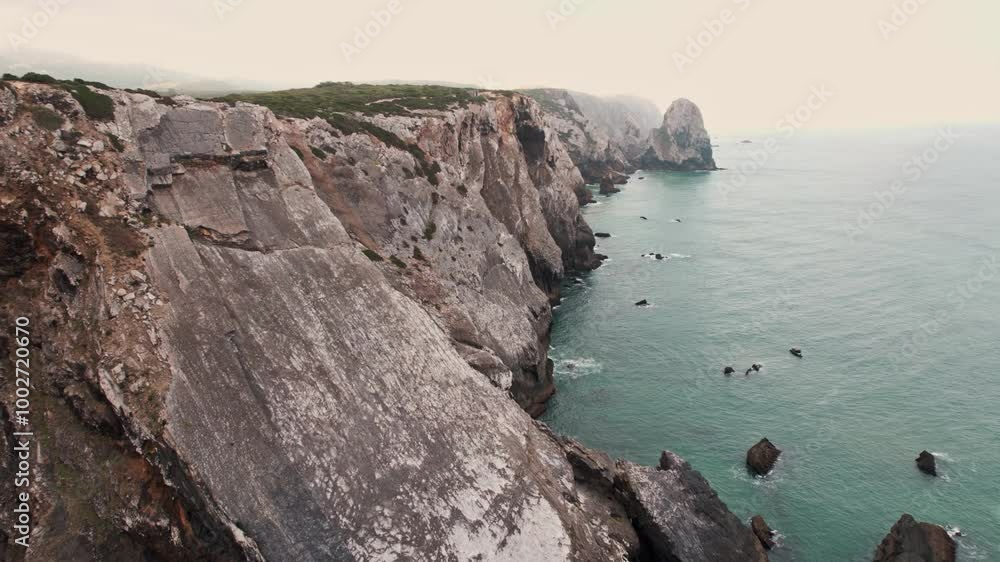 Scenic aerial view of the beautiful rock formations and cliffs along the coast of Adraga Beach in Portugal. Scenic aerial view of the beautiful rock formations and cliffs along the coast of Adraga Beach in Portugal.