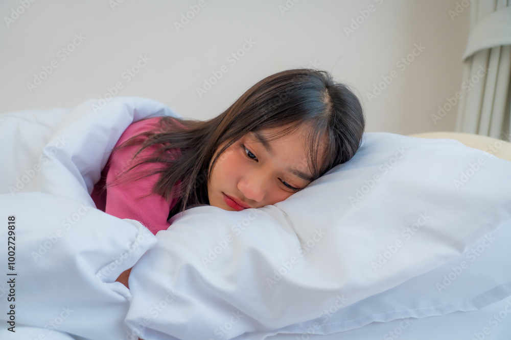 Asian young woman lying down on bed with disappointed face in bedroom at home. Teenager girl feel stressed and depressed with life problems, don’t want to wake up in the morning. Asian young woman lying down on bed with disappointed face in bedroom at home. Teenager girl feel stressed and depressed with life problems, don’t want to wake up in the morning.