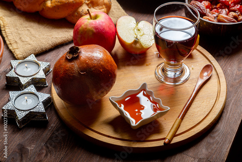 Hala, honey, apple and grenade and wine and traditional dishes on the table with menora and burning candles in honor of Rosh and Shan