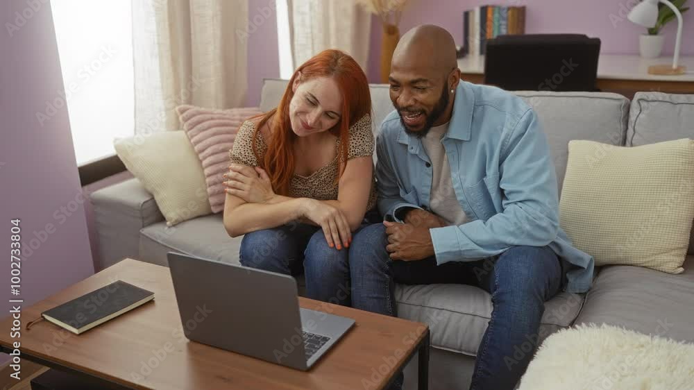 Couple on a video call at home sitting on a sofa in the living room, showing love and togetherness, man and woman enjoying their time indoors with a laptop Couple on a video call at home sitting on a sofa in the living room, showing love and togetherness, man and woman enjoying their time indoors with a laptop