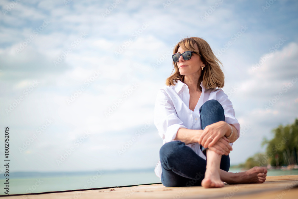 Full length of a blond haired woman relaxing by the lake Full length of a blond haired woman relaxing by the lake
