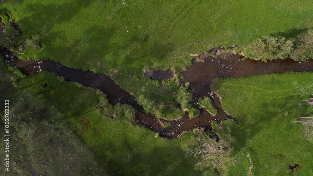 Top Down Aerial View of Creek Between Green Pastures, Idyllic Mountain Landscape Top Down Aerial View of Creek Between Green Pastures, Idyllic Mountain Landscape
