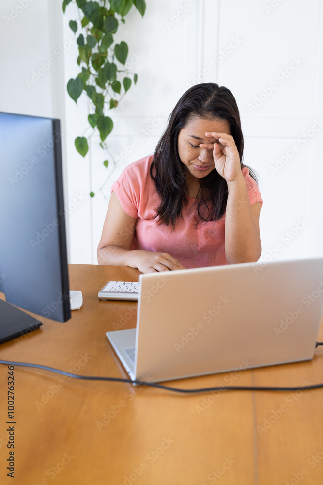 Working from home, woman feeling stressed while using laptop and desktop computer Working from home, woman feeling stressed while using laptop and desktop computer