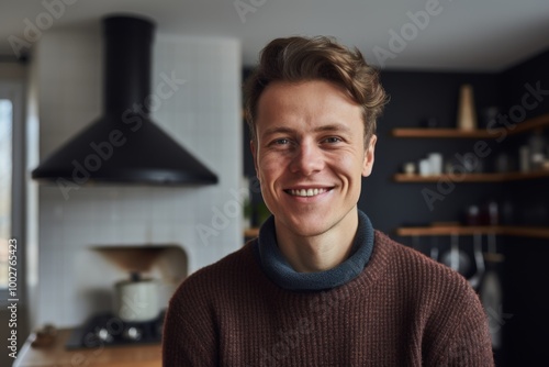 Portrait of a grinning man in his 20s wearing a classic turtleneck sweater isolated in scandinavian-style interior background