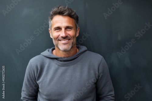 Portrait of a smiling man in his 40s wearing a thermal fleece pullover in bare concrete or plaster wall