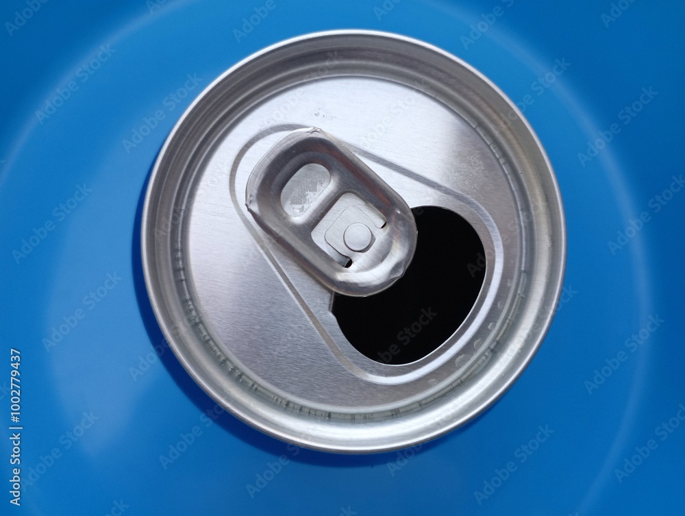 An open metal can with a drink on a blue background. Top view of an empty beverage can. An open metal can with a drink on a blue background. Top view of an empty beverage can.