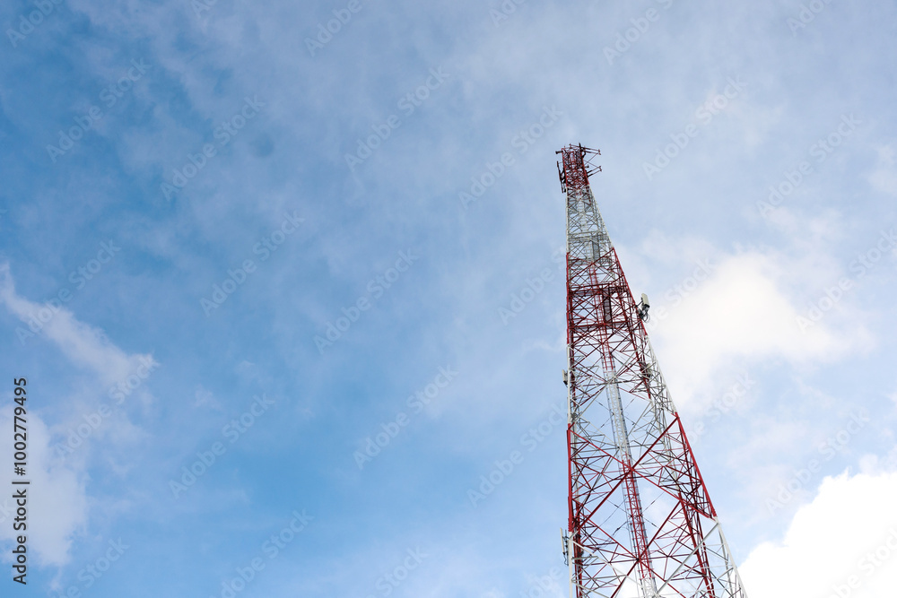 A tall tower with a red and white top is seen against a blue sky A tall tower with a red and white top is seen against a blue sky