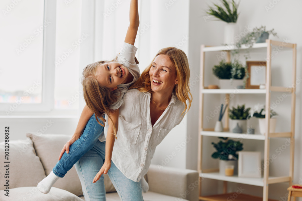 Joyful mother and daughter playing and laughing together in a cozy living room filled with natural light Joyful mother and daughter playing and laughing together in a cozy living room filled with natural light