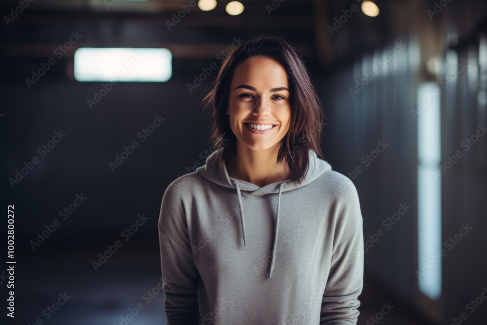 Φωτογραφία Portrait of a grinning woman in her 30s sporting a comfortable hoodie in empty m
