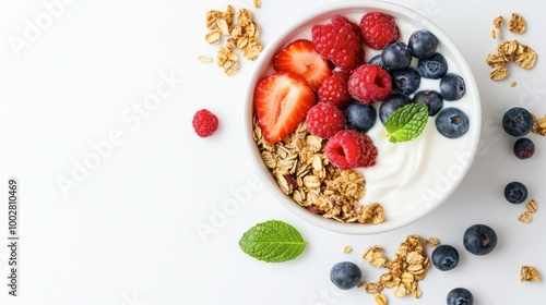 Overhead view of a breakfast bowl with yogurt, fruits, and granola. Copy space on a white background.