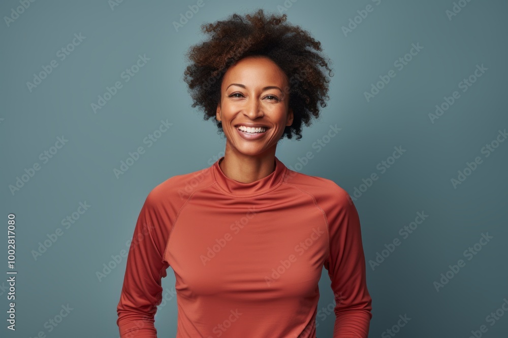 Portrait of a smiling afro-american woman in her 40s wearing a moisture-wicking running shirt in front of plain white digital canvas Portrait of a smiling afro-american woman in her 40s wearing a moisture-wicking running shirt in front of plain white digital canvas