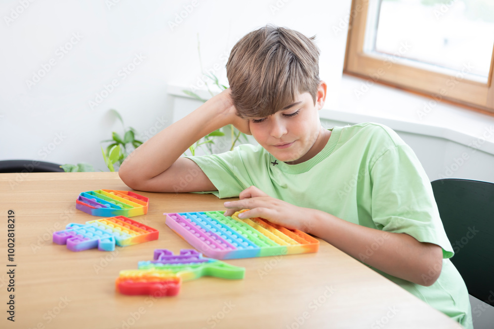 Cute happy boy plays with rainbow reusable bubble wrap popping fidget Cute happy boy plays with rainbow reusable bubble wrap popping fidget