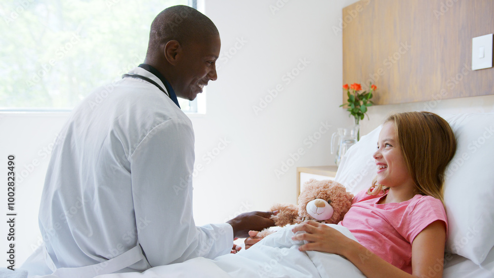 Male Doctor Visiting Girl Lying In Hospital Bed Hugging Teddy Bear Male Doctor Visiting Girl Lying In Hospital Bed Hugging Teddy Bear