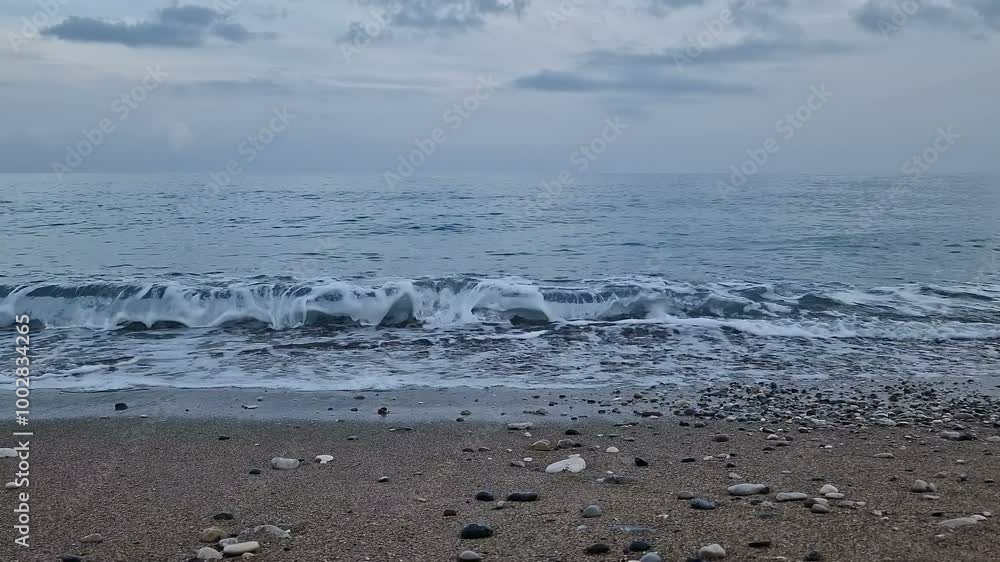 Waves in the sea. A pebble beach. The shore of the sea beach with waves in the ocean. Waves in the sea. A pebble beach. The shore of the sea beach with waves in the ocean.