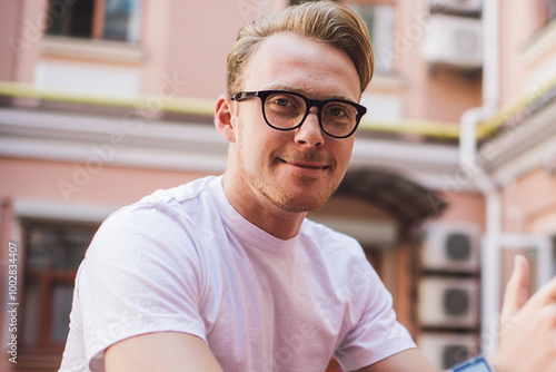 Portrait of male blogger with modern digital tablet for online communication smiling at camera during youth lifestyle time, millennial generation in optical spectacles for provide eyes protection