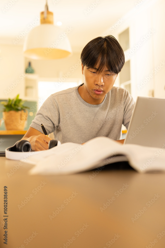 Studying , young man using laptop and writing in notebook Studying , young man using laptop and writing in notebook