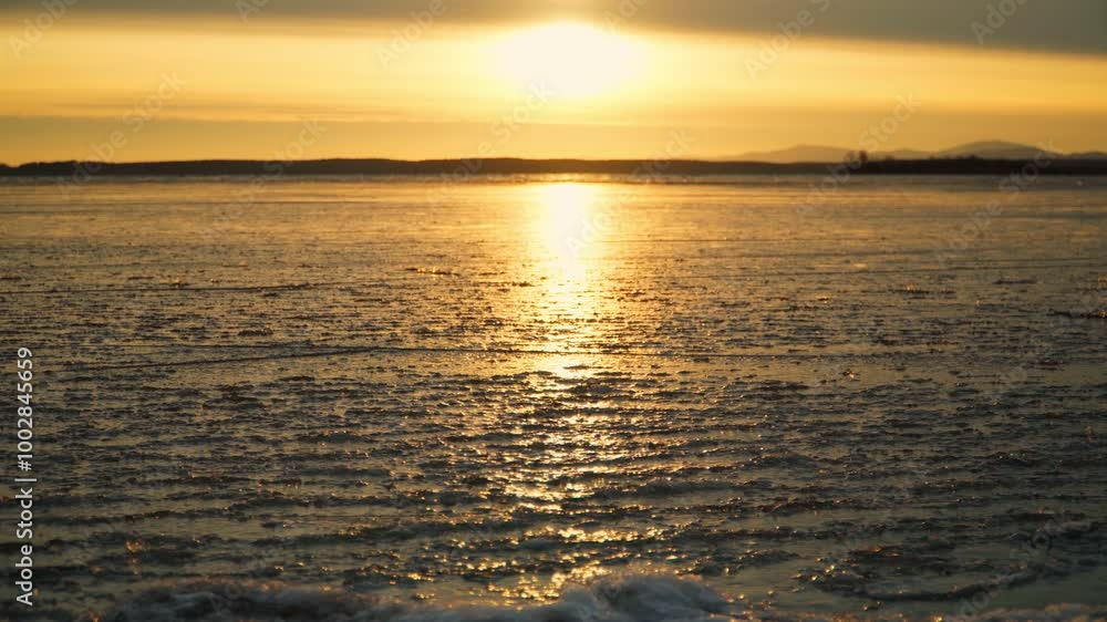 Close-up of a thin ice crust on the water surface of the lake in the rays of the setting sun. The fragile icy surface is undulating. Dangerous thin ice. Close-up of a thin ice crust on the water surface of the lake in the rays of the setting sun. The fragile icy surface is undulating. Dangerous thin ice.