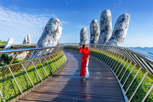 Asian female tourist walks on golden bridge in Ba Na hills, Danang, Vietnam.