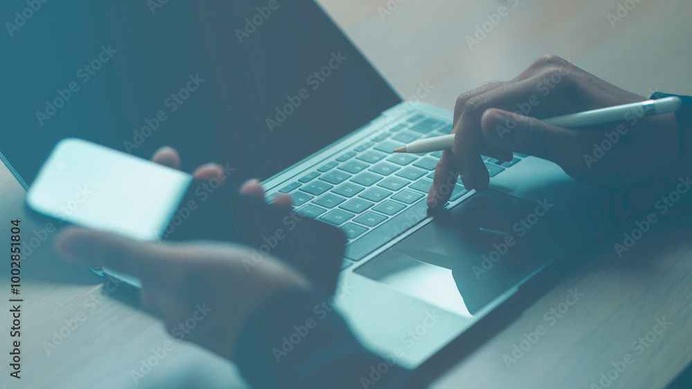 A person is using a laptop and a cell phone at the same time