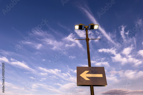 Direction arrow and street lamp on the sky photo