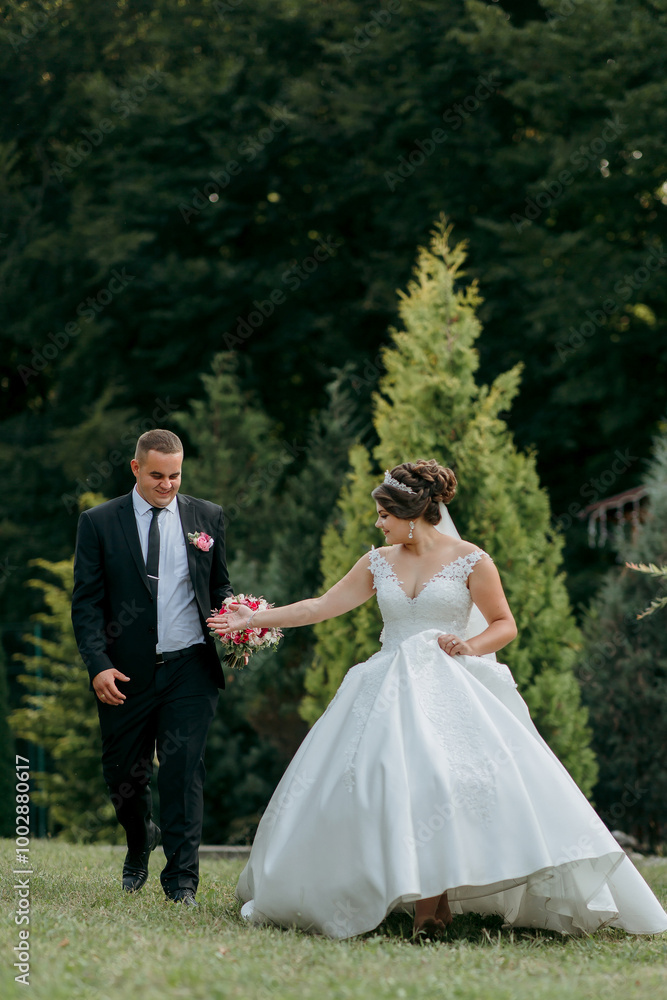 A bride and groom are walking together in a park. The bride is holding a bouquet and the groom is holding her hand. Scene is happy and romantic A bride and groom are walking together in a park. The bride is holding a bouquet and the groom is holding her hand. Scene is happy and romantic
