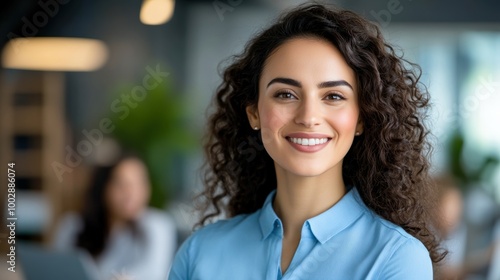 Smiling woman with curly hair in a modern office setting, exuding confidence and professionalism.