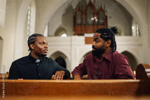 Priest listening to man talking in church photo