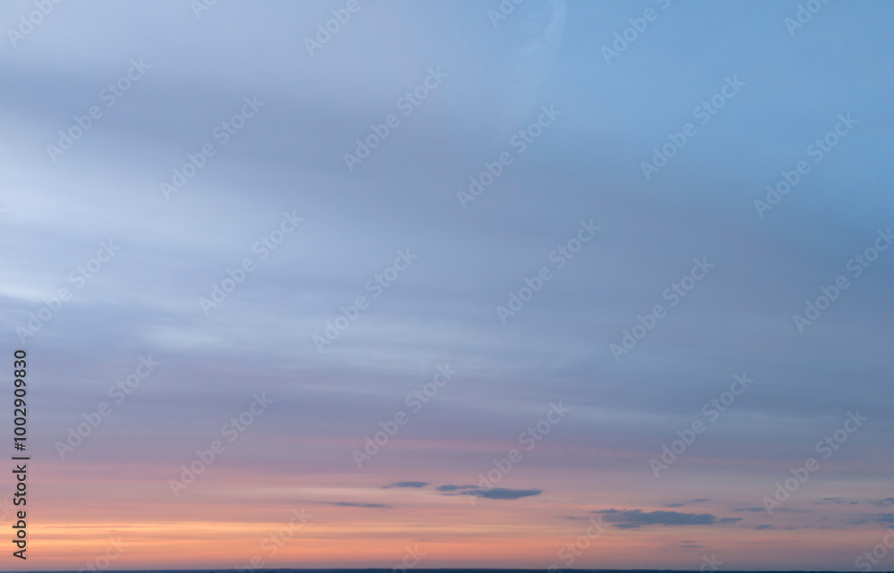 Fototapeta premium Beautiful pastel-colored sky at sunset with soft clouds. Peaceful evening landscape with gradient colors of blue and pink in the horizon. Ideal for backgrounds or serene scenes.