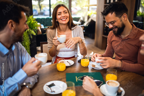 Group of friends chilling at the cafe. Talking, laughing and drinking coffee and orange juice.