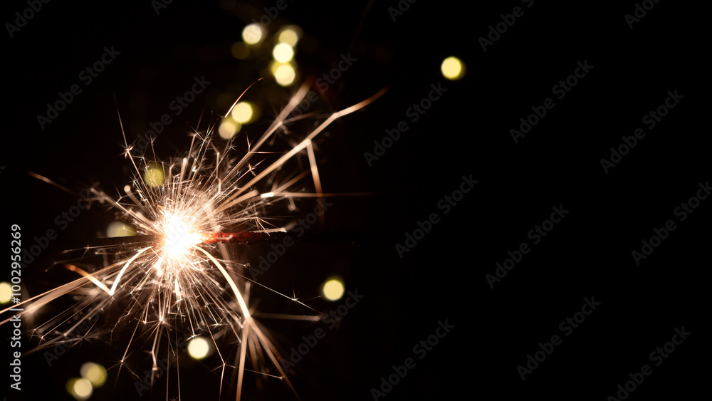 Obraz premium Bengal fire on blurred background with bokeh, new year and Christmas holidays, banner