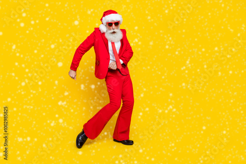 Full length photo of funky cool retired guy wear red tux claus hat dancing empty space isolated yellow color background