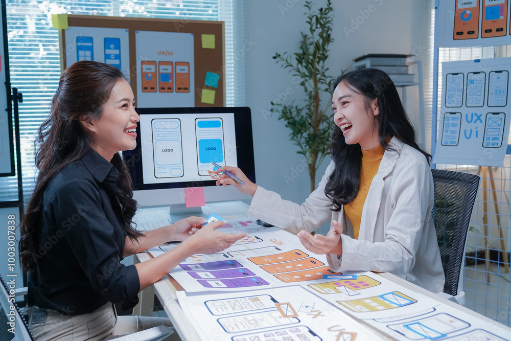 Two asian women working as ui/ux designers collaborating on a new ...