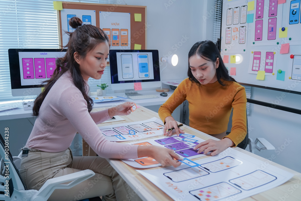 Two female ui/ux designers are working together to develop a mobile ...