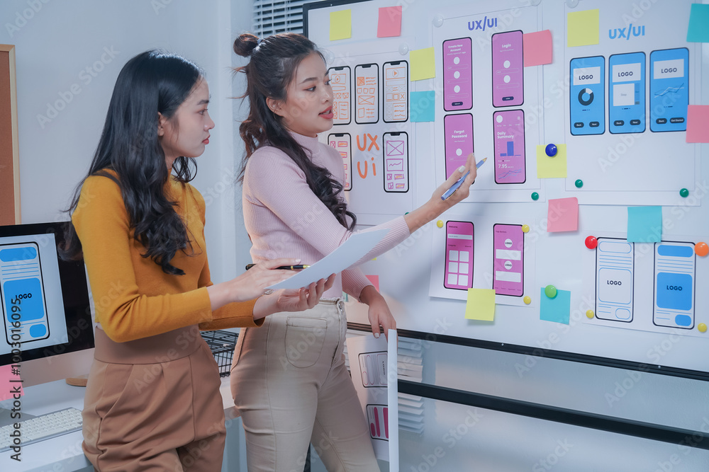 Two female ui/ux designers are exchanging ideas about the design of a ...