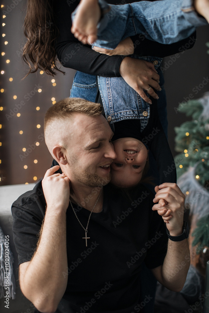 Obraz premium Caucasian father and young girl enjoying playful bonding time at home. Father expresses joy as daughter hangs upside down, showcasing closeness and fun.